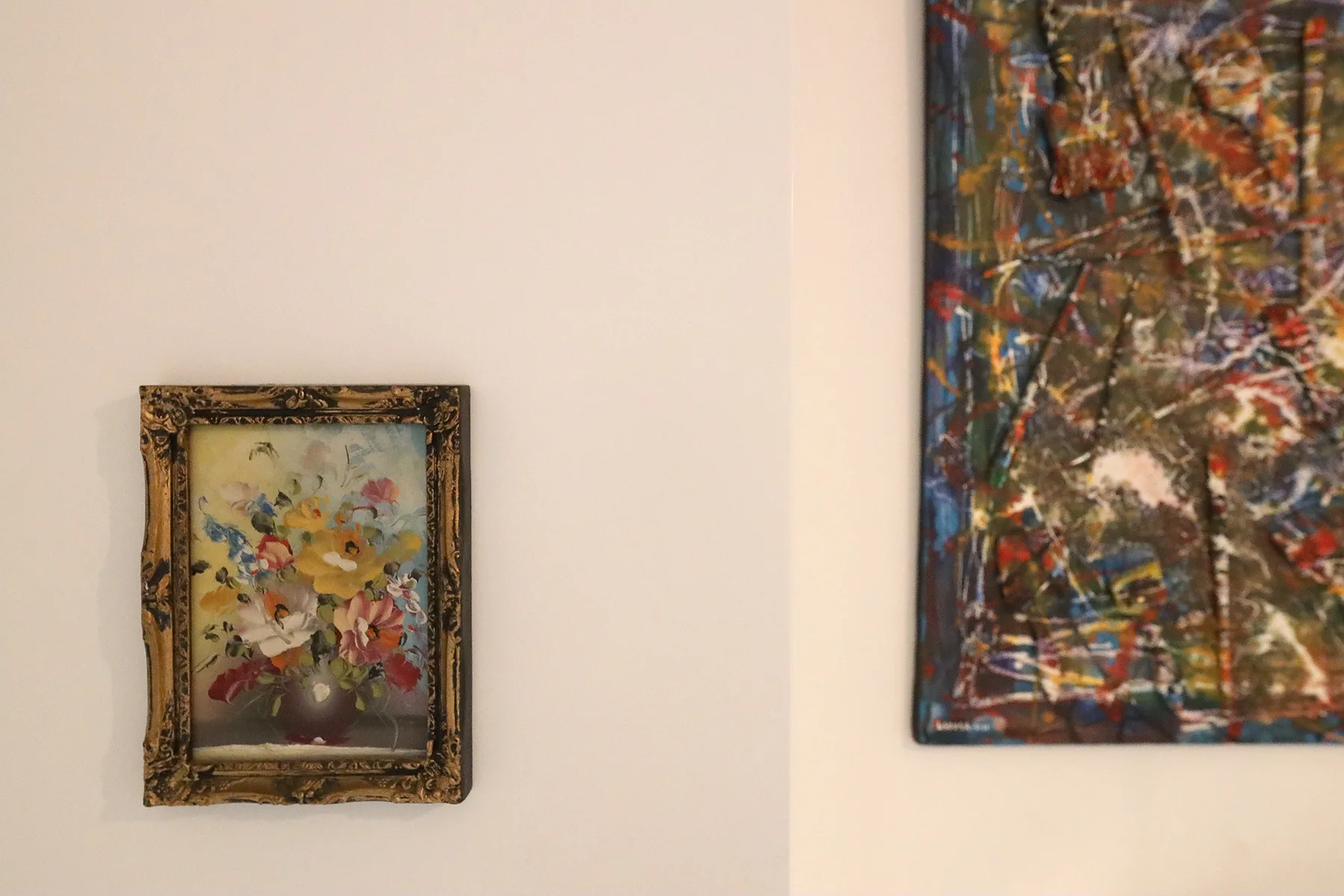 Two paintings hang on a pale wall.