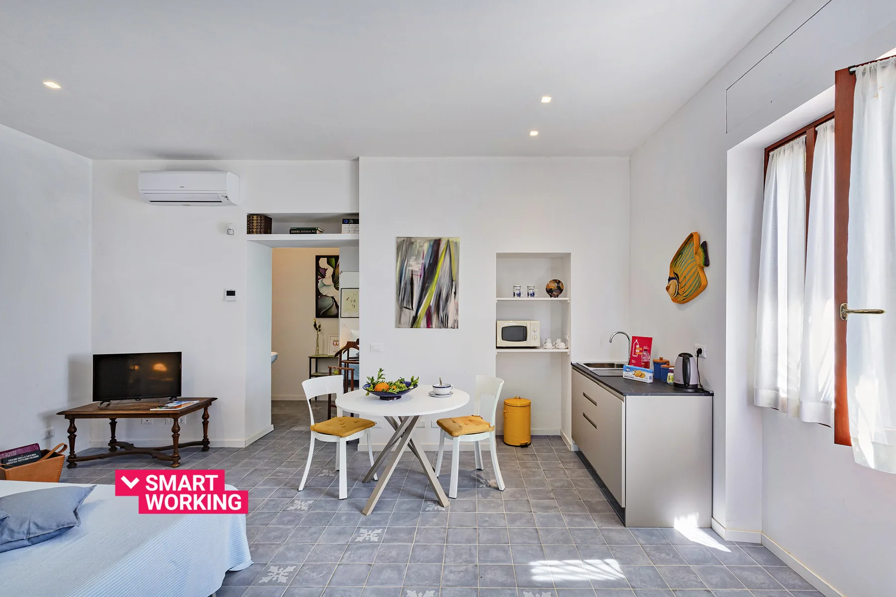 Un estudio luminoso con cama, mesa de comedor y cocina pequeña.