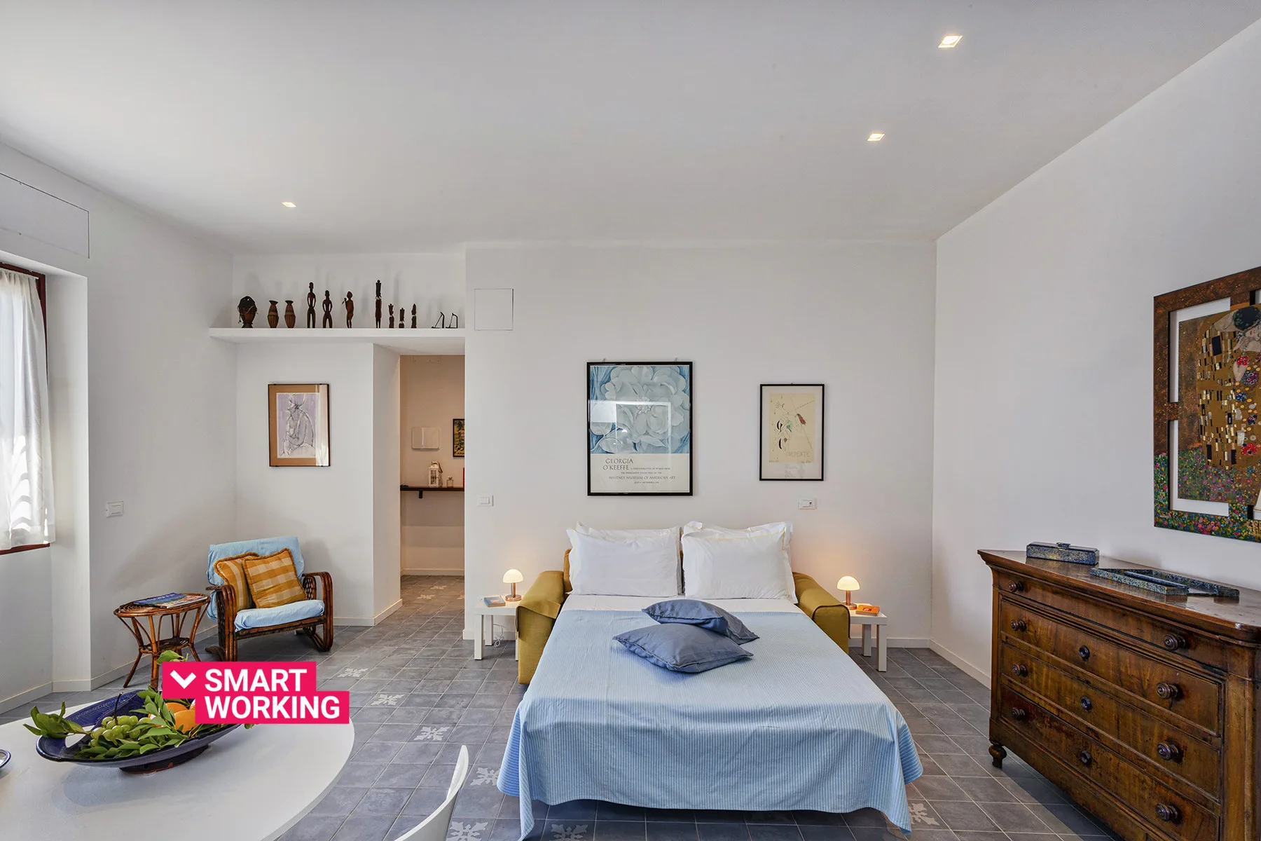 Un dormitorio con una cama, cuadros enmarcados y una cómoda de madera.