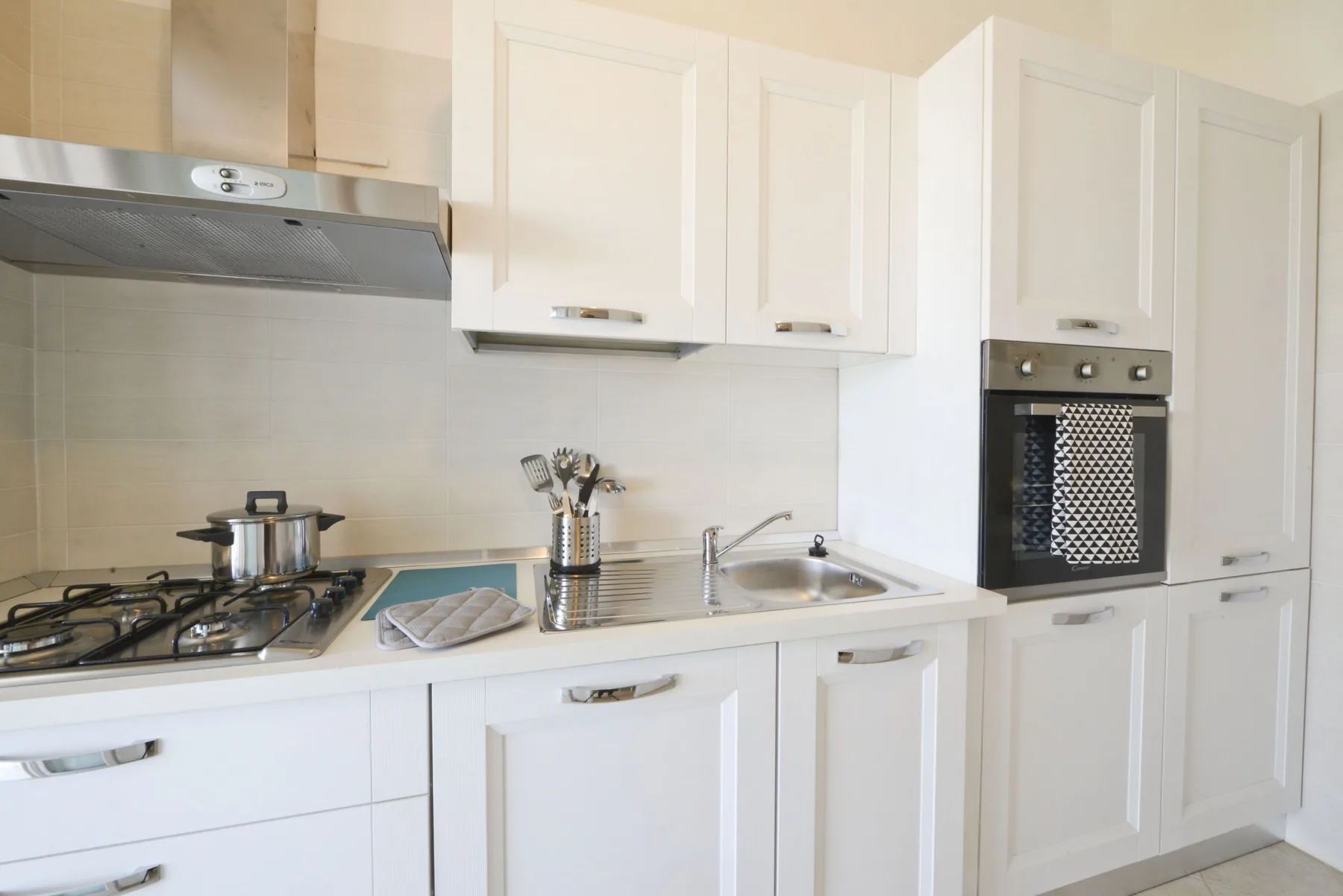 A bright kitchen with white cabinets, a gas cooktop, and a sink.