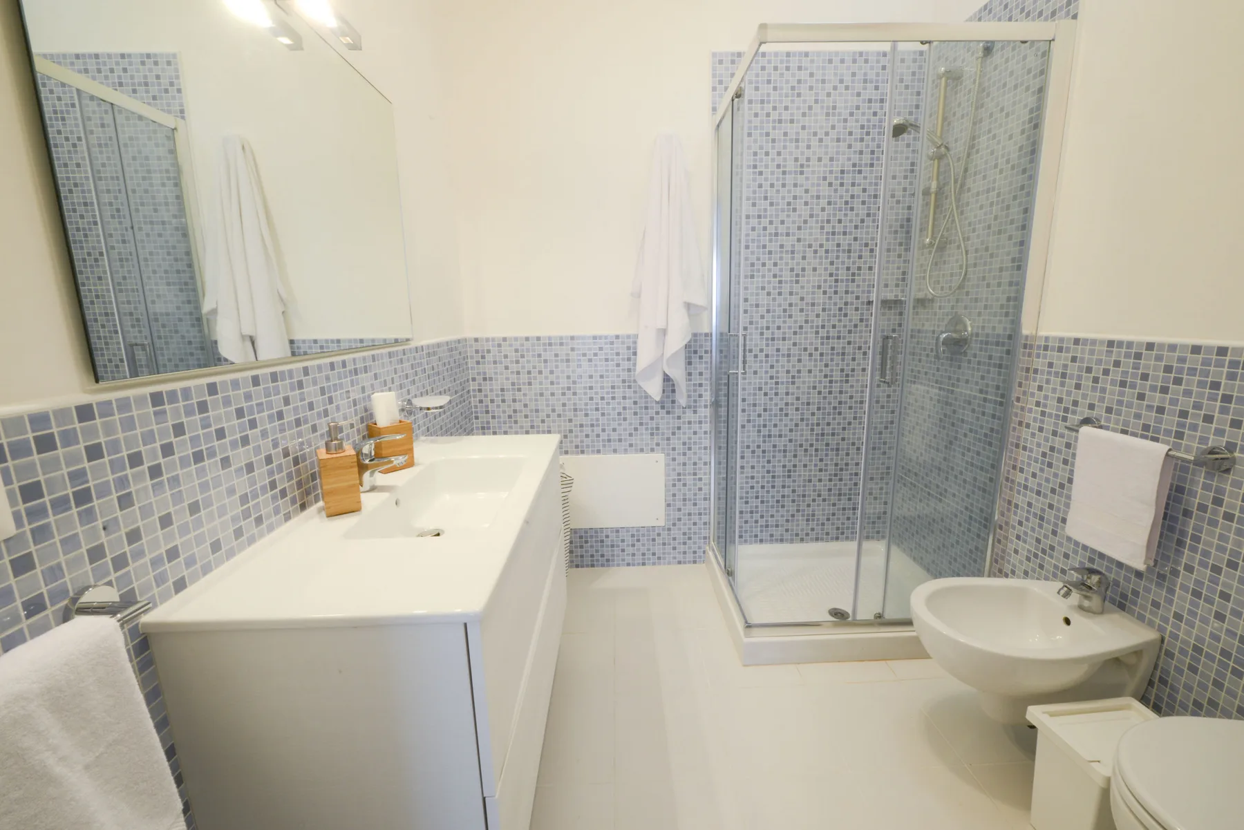 A tiled bathroom with a sink, mirror, and glass shower.