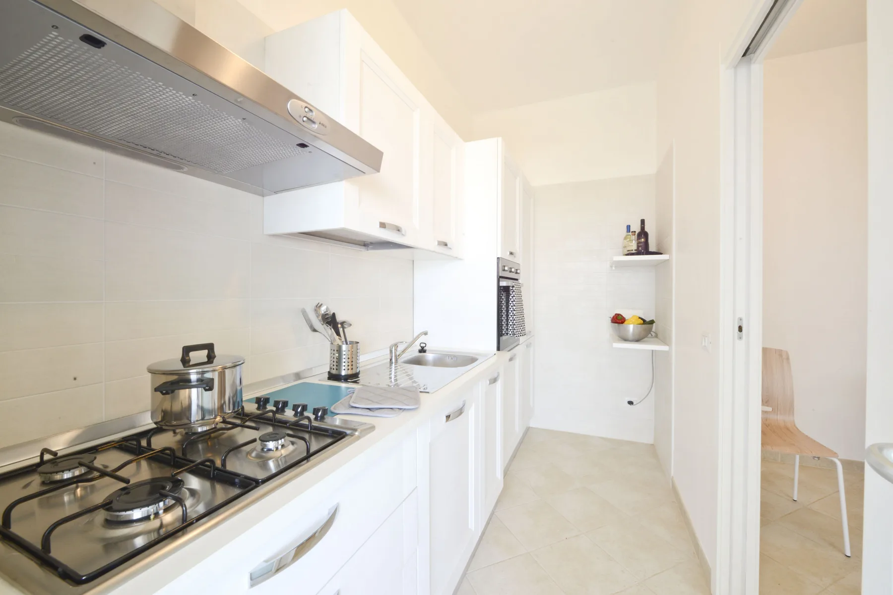 A bright kitchen with a gas cooktop and white cabinets.