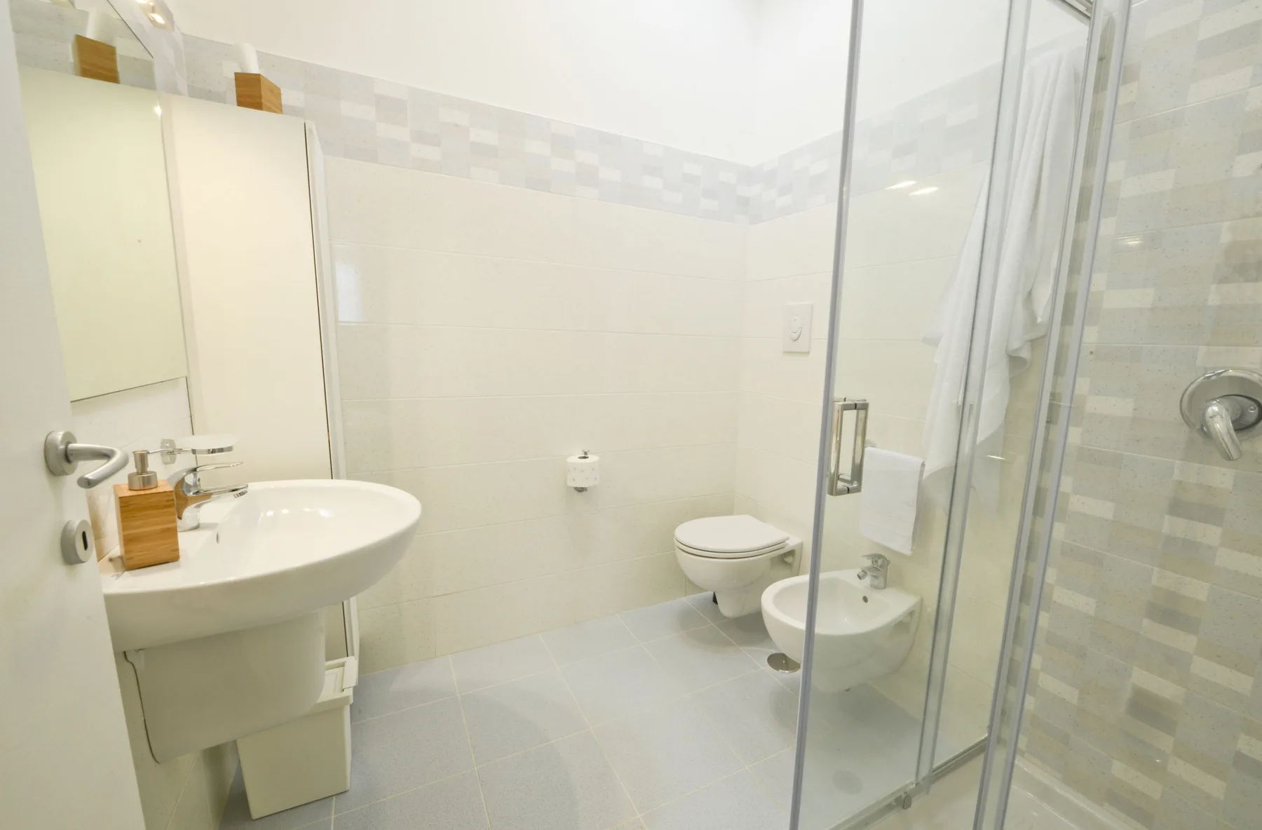 A bright bathroom with a sink, toilet, and glass shower.