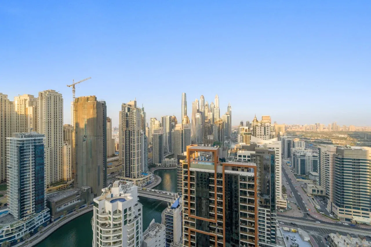 City skyline with densely clustered high-rise buildings and a road in the foreground.