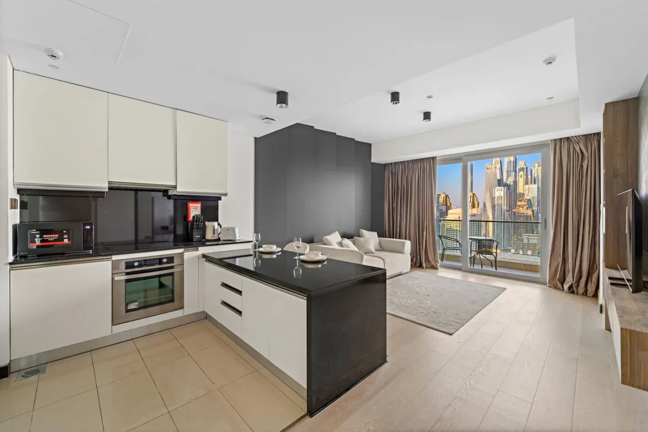 An open-plan kitchen and living area with a dining counter beside floor-to-ceiling windows.
