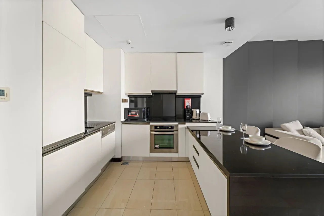 A modern kitchen with white cabinets and a dark countertop island.
