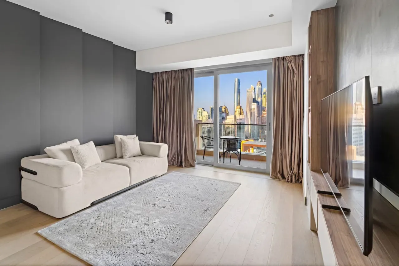 A modern living room with seating and large windows overlooking the city.