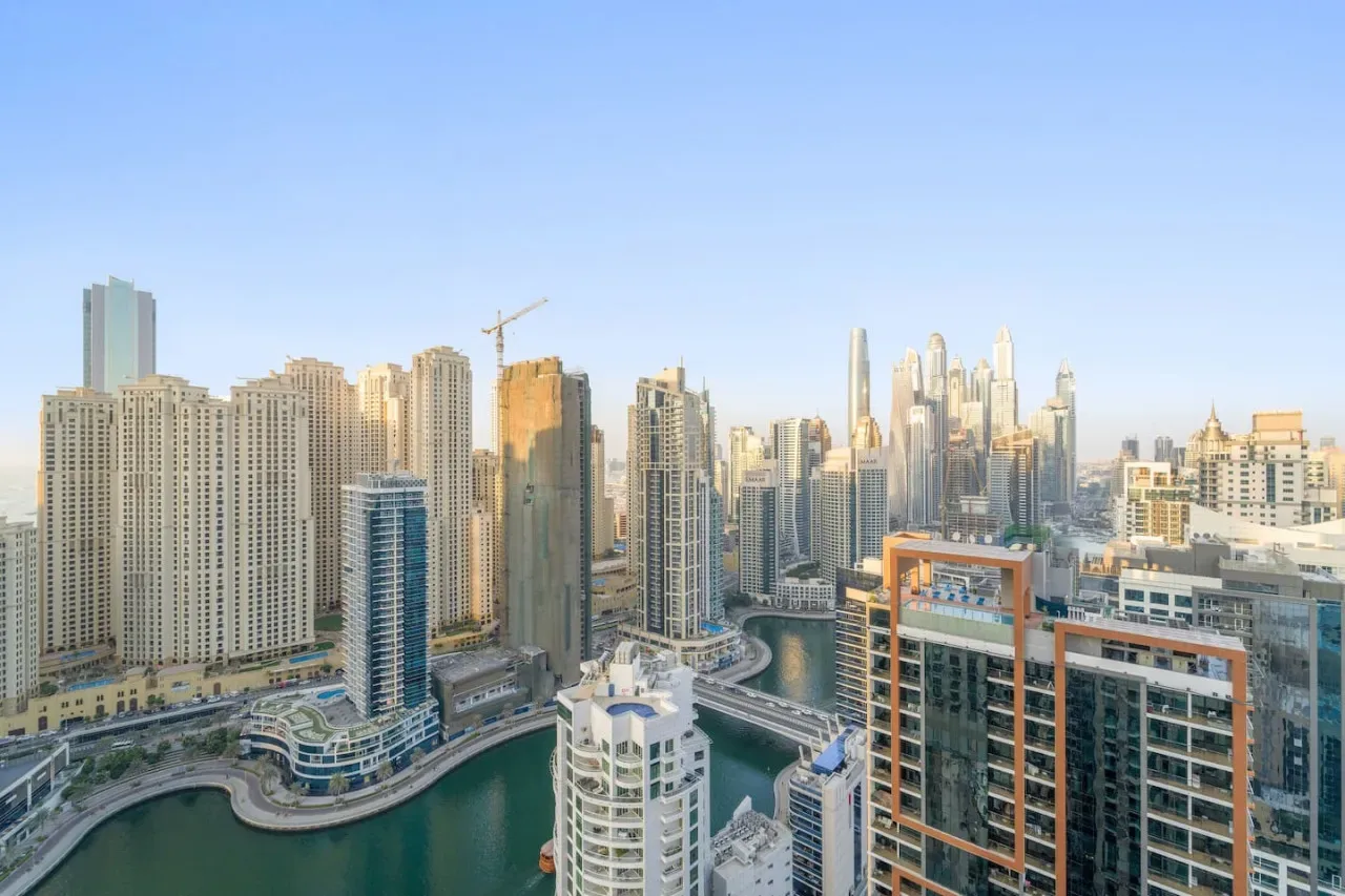 A city skyline of high-rise buildings surrounds a curving canal.