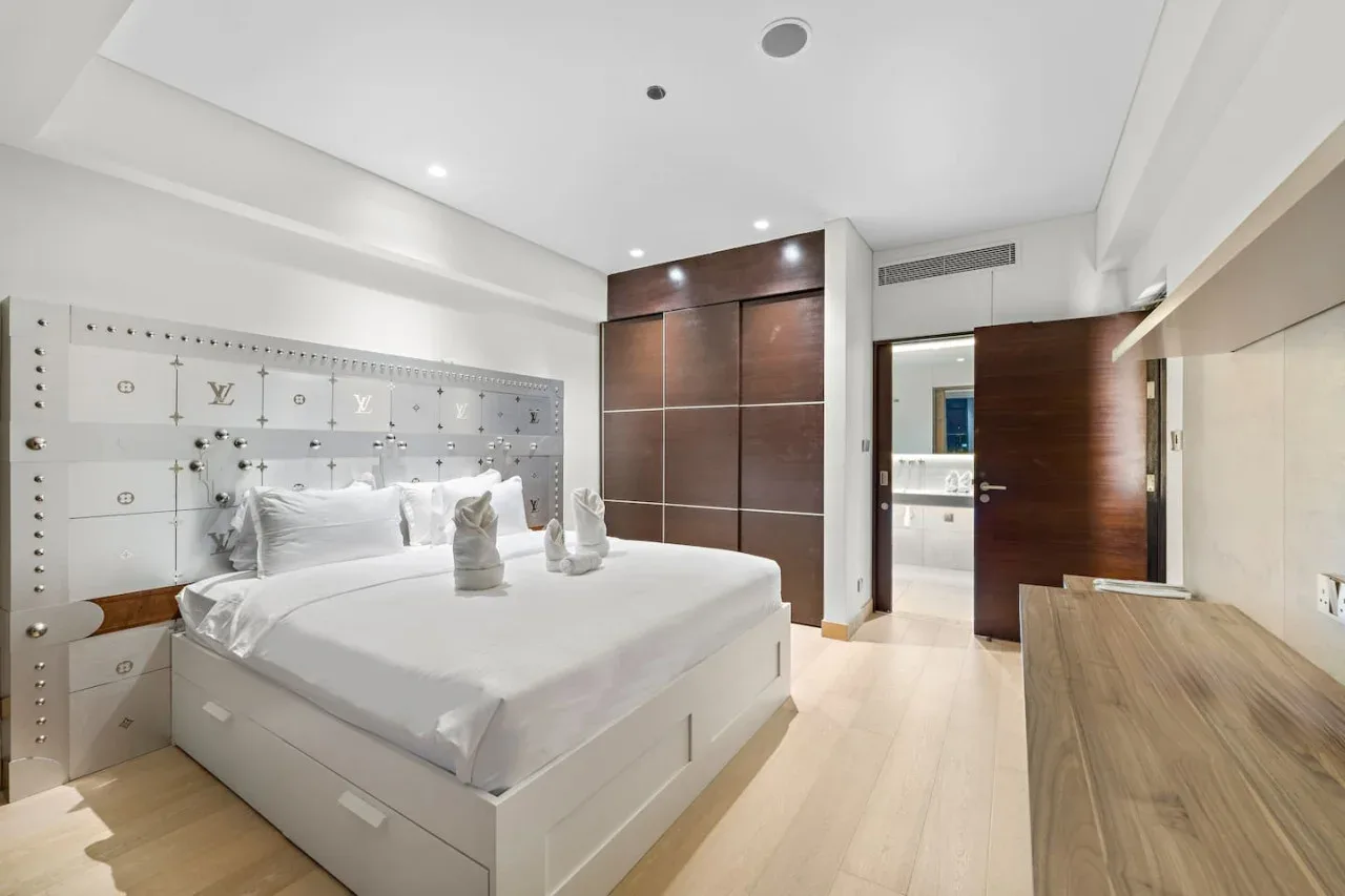 A bedroom with a large bed, white bedding, and a wood-finish wardrobe.