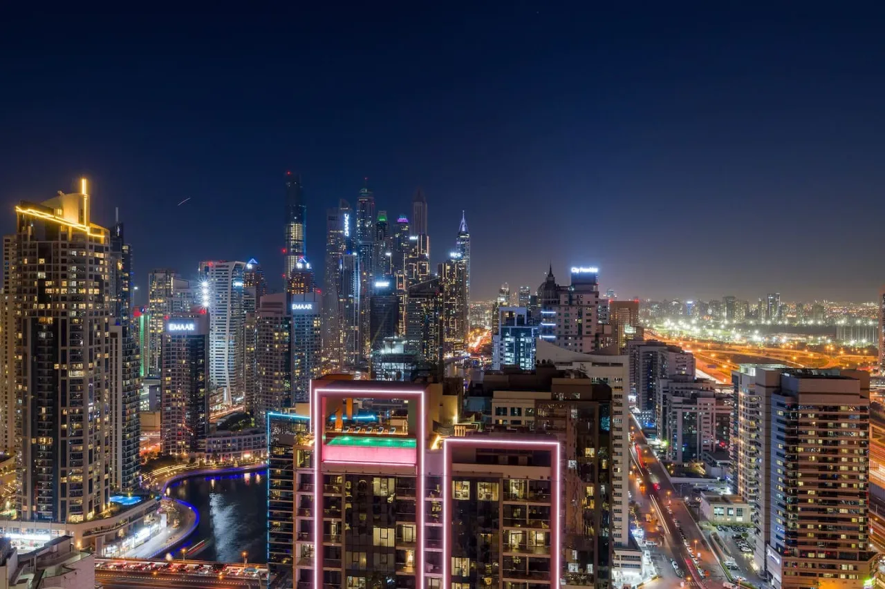 A nighttime city skyline with illuminated skyscrapers and busy roads.