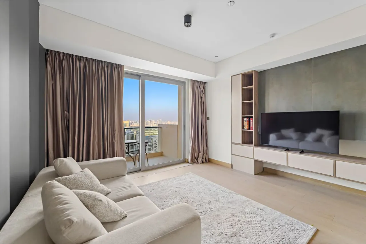 A living room with seating, a television, and sliding glass doors opening onto a balcony.