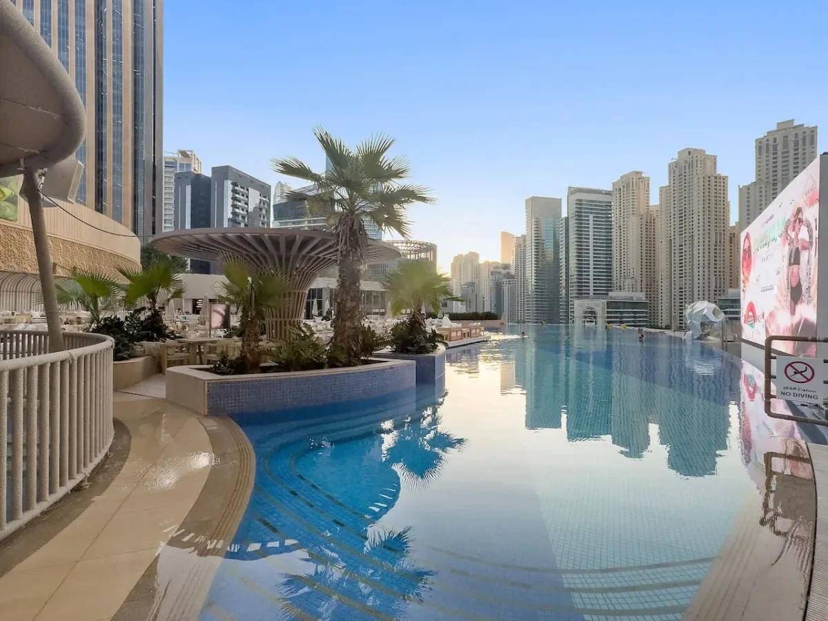 A rooftop swimming pool overlooks a skyline of high-rise buildings.