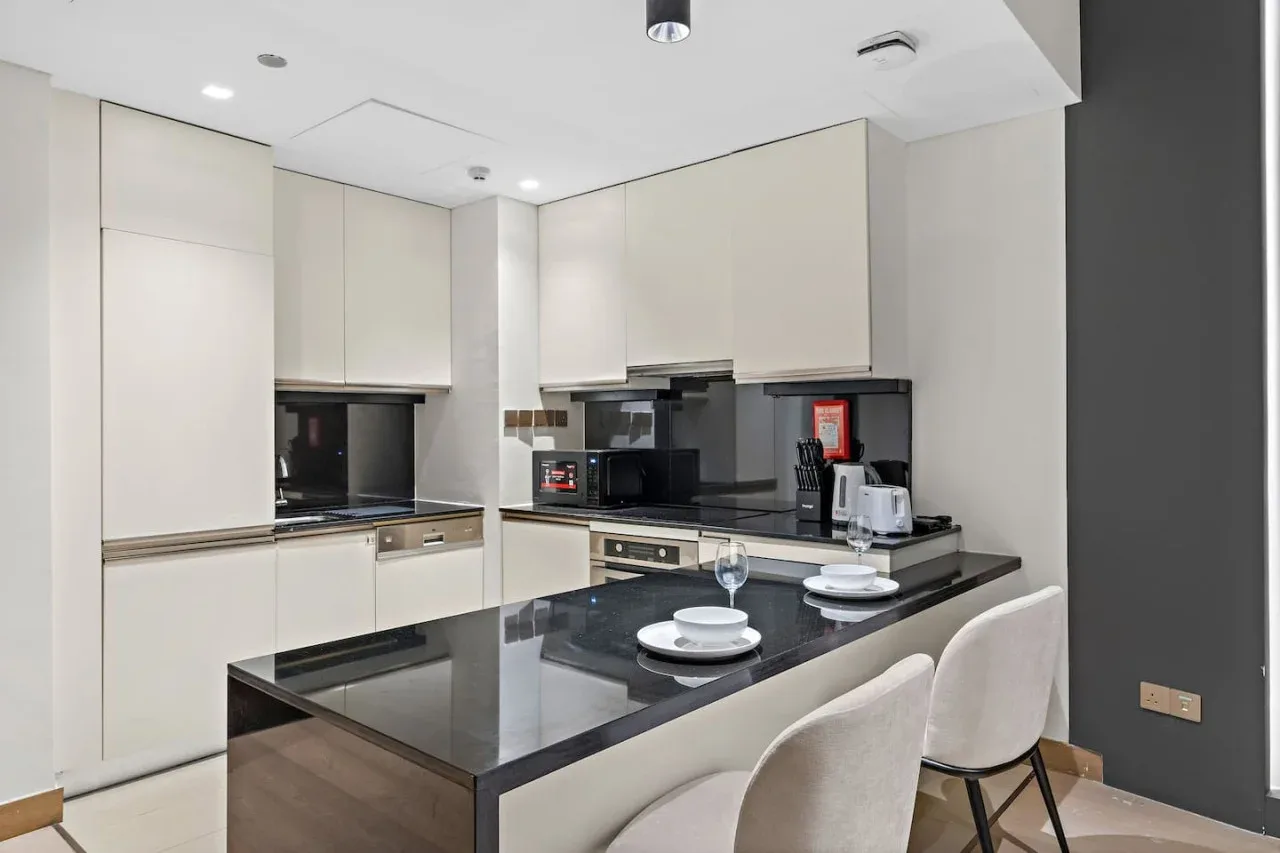 A modern kitchen with light cabinetry and a dark island with seating.