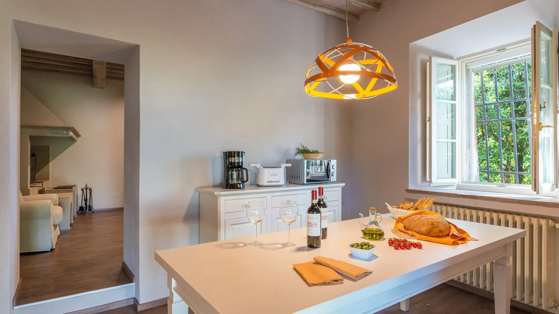 Comedor con una mesa puesta junto a una gran ventana abierta.