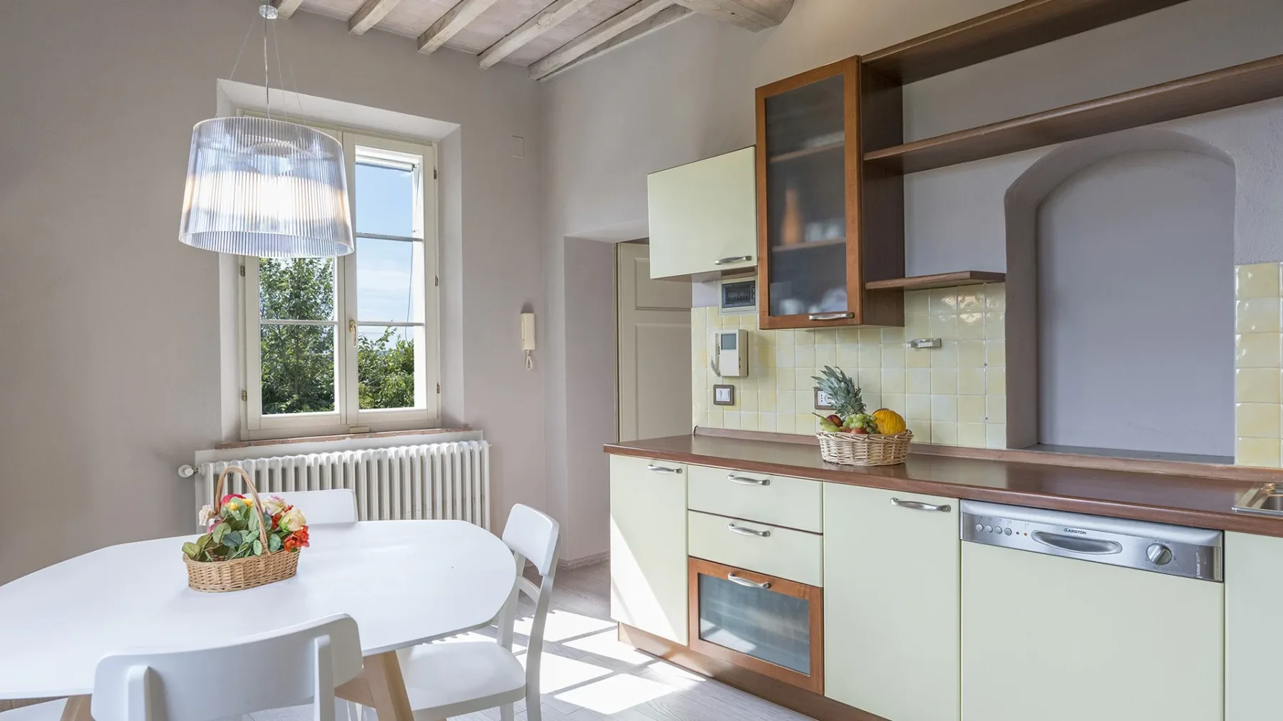 Una cocina luminosa con gabinetes claros y una mesa de comedor junto a la ventana.