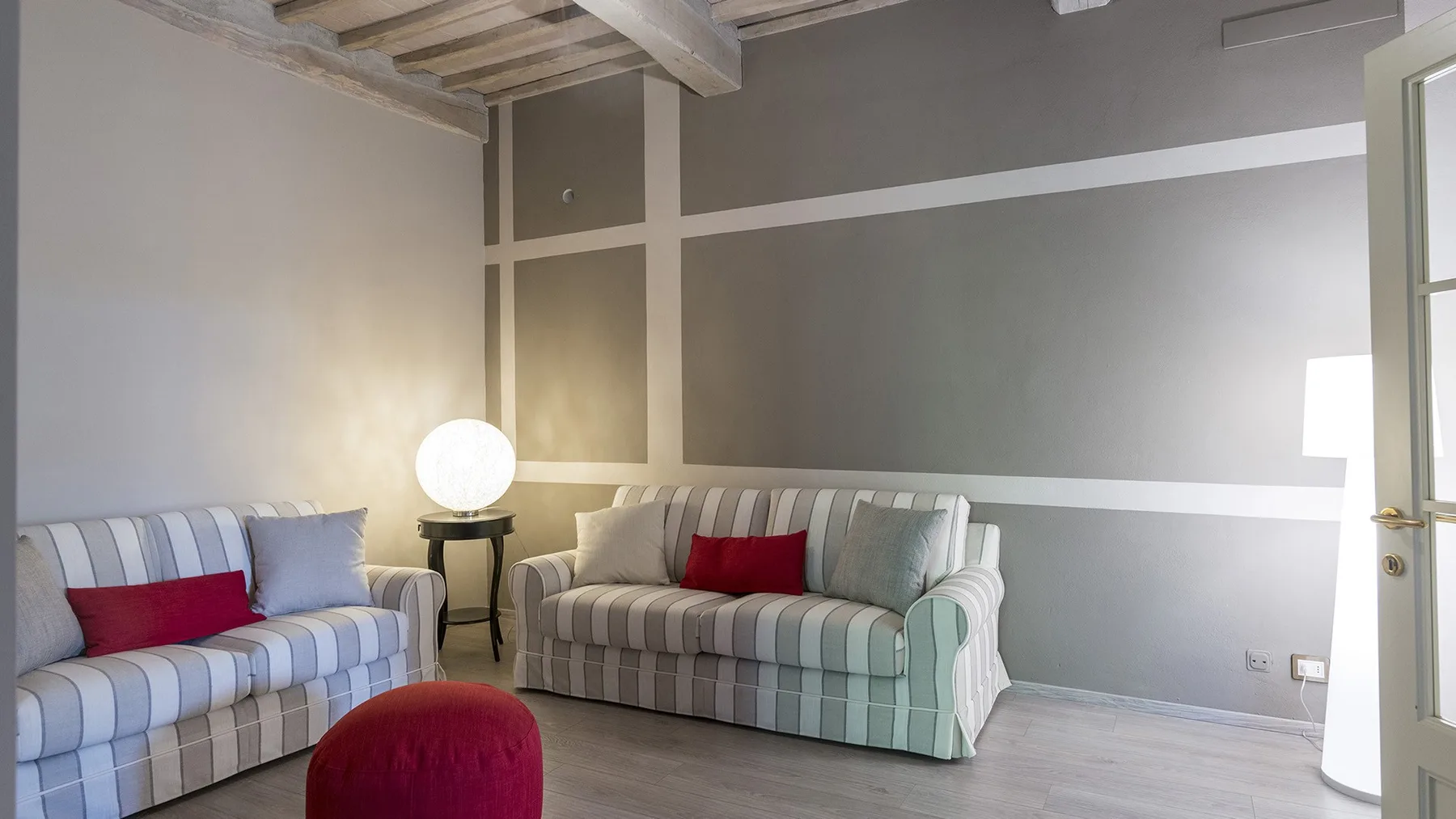 Una sala de estar con asientos a rayas y una pequeña mesa auxiliar redonda.