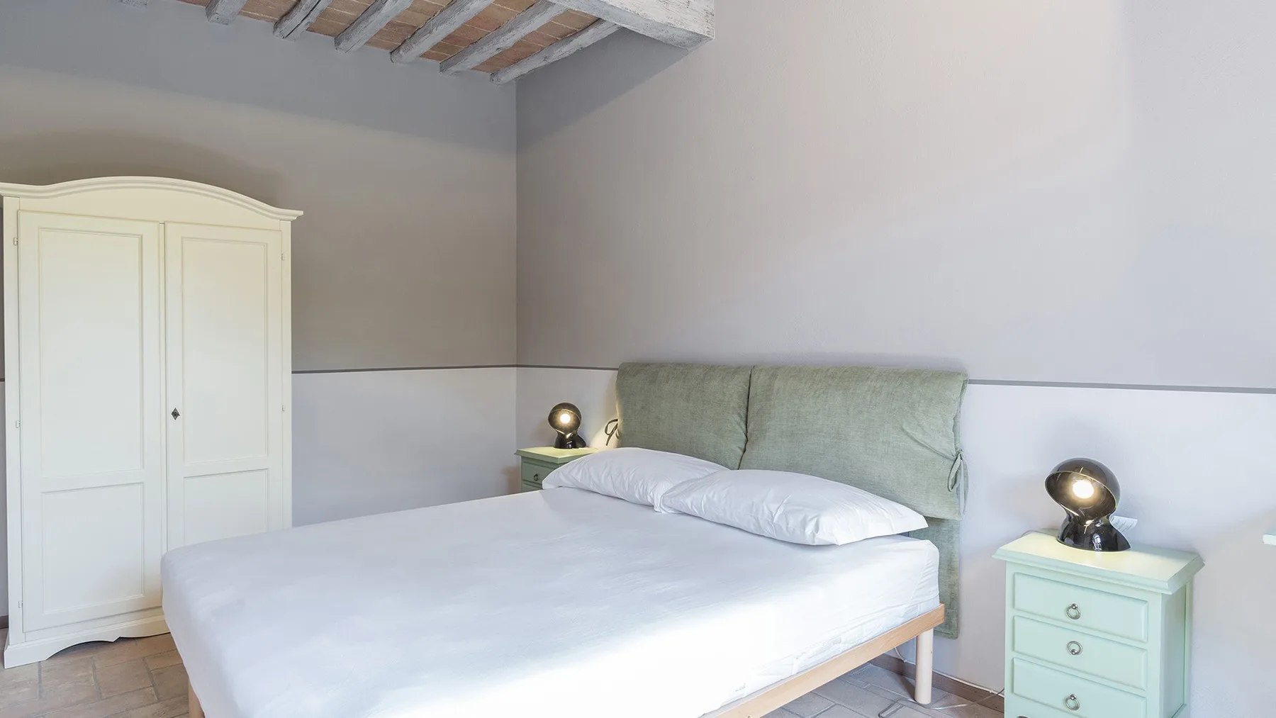 Un dormitorio con una cama, un cabecero verde claro y un armario.