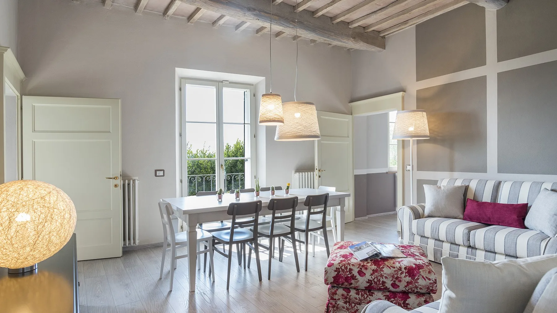 Una luminosa zona de comedor y estar con mesa, sillas y asientos a rayas.