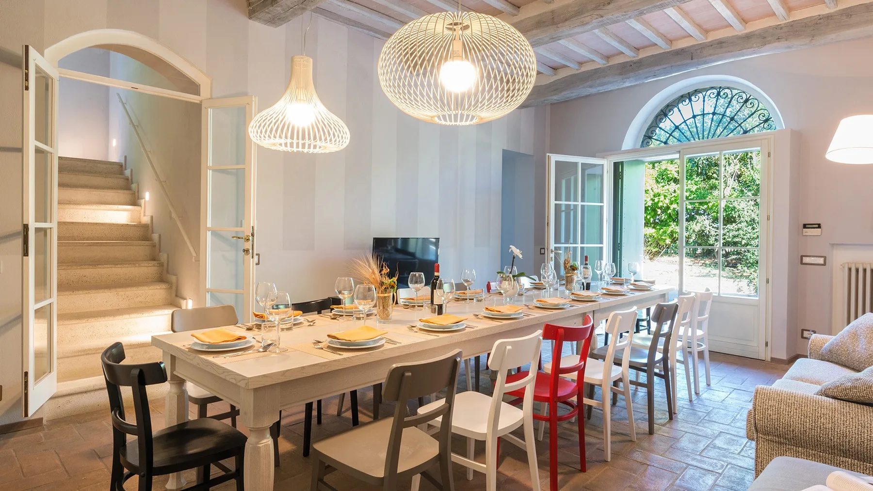 Un comedor con una mesa larga preparada para comer junto a puertas abiertas.