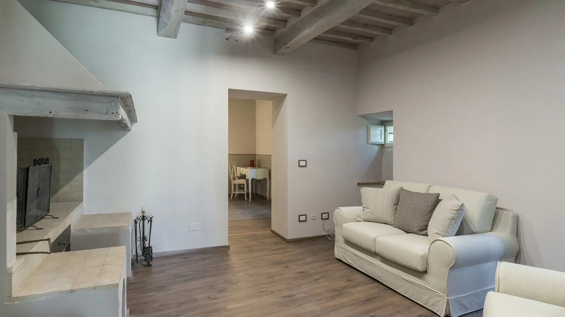 Una sala de estar con un sofá claro y una chimenea.