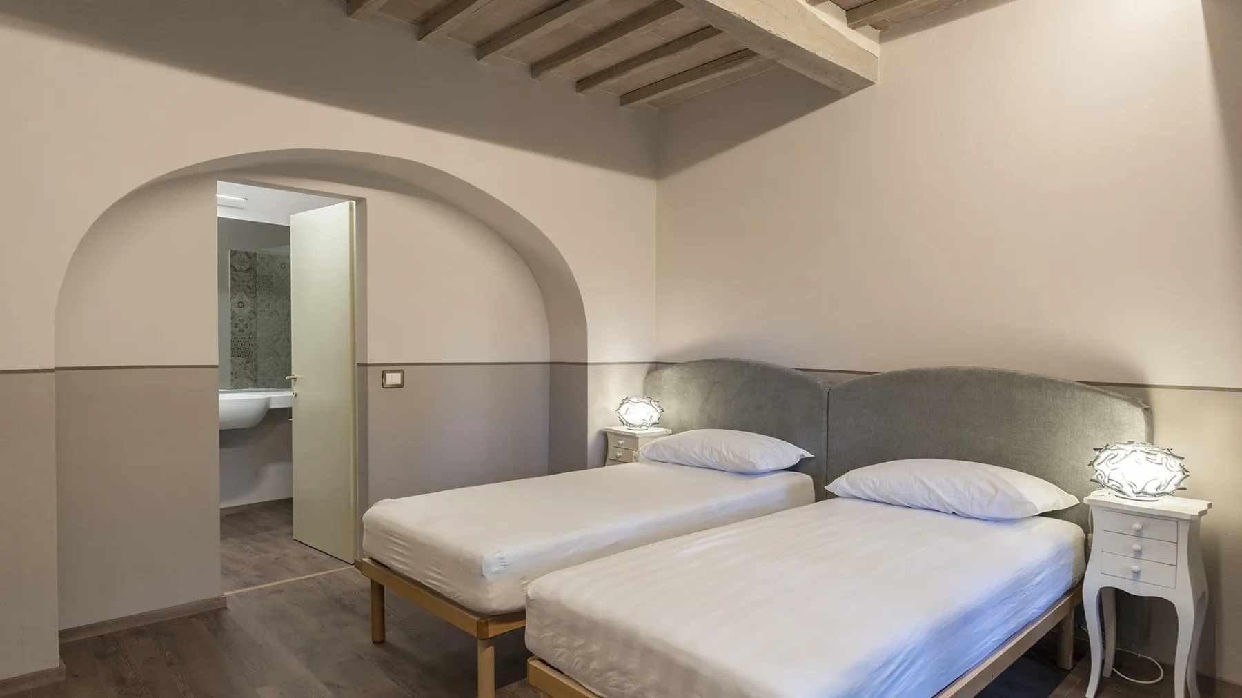 Un dormitorio con dos camas y un arco que da a un baño.
