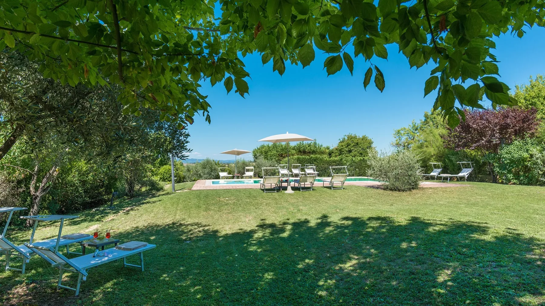 Un jardín ajardinado con césped, asientos al aire libre y una piscina.