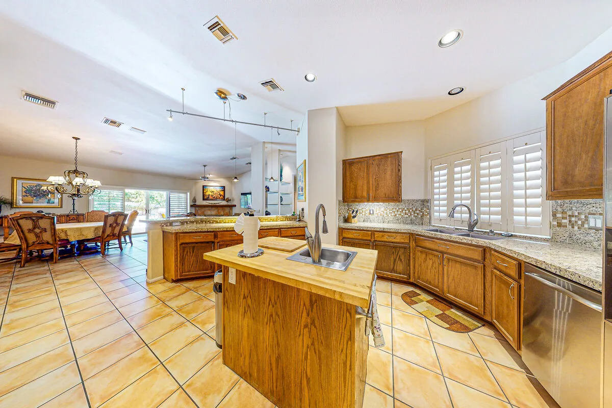 Una cocina amplia con gabinetes de madera, una isla central y piso de baldosas.