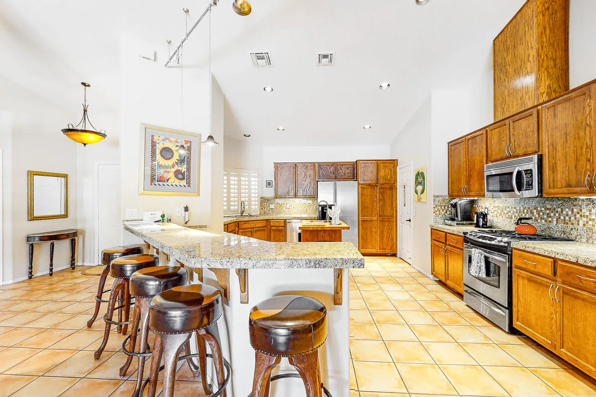 Una cocina amplia con gabinetes de madera, electrodomésticos de acero inoxidable y una isla central.