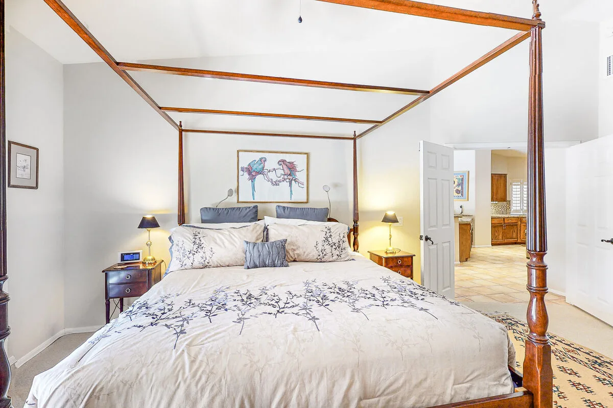 Un dormitorio con una cama con dosel grande y una puerta abierta hacia una habitación con suelo de baldosas.