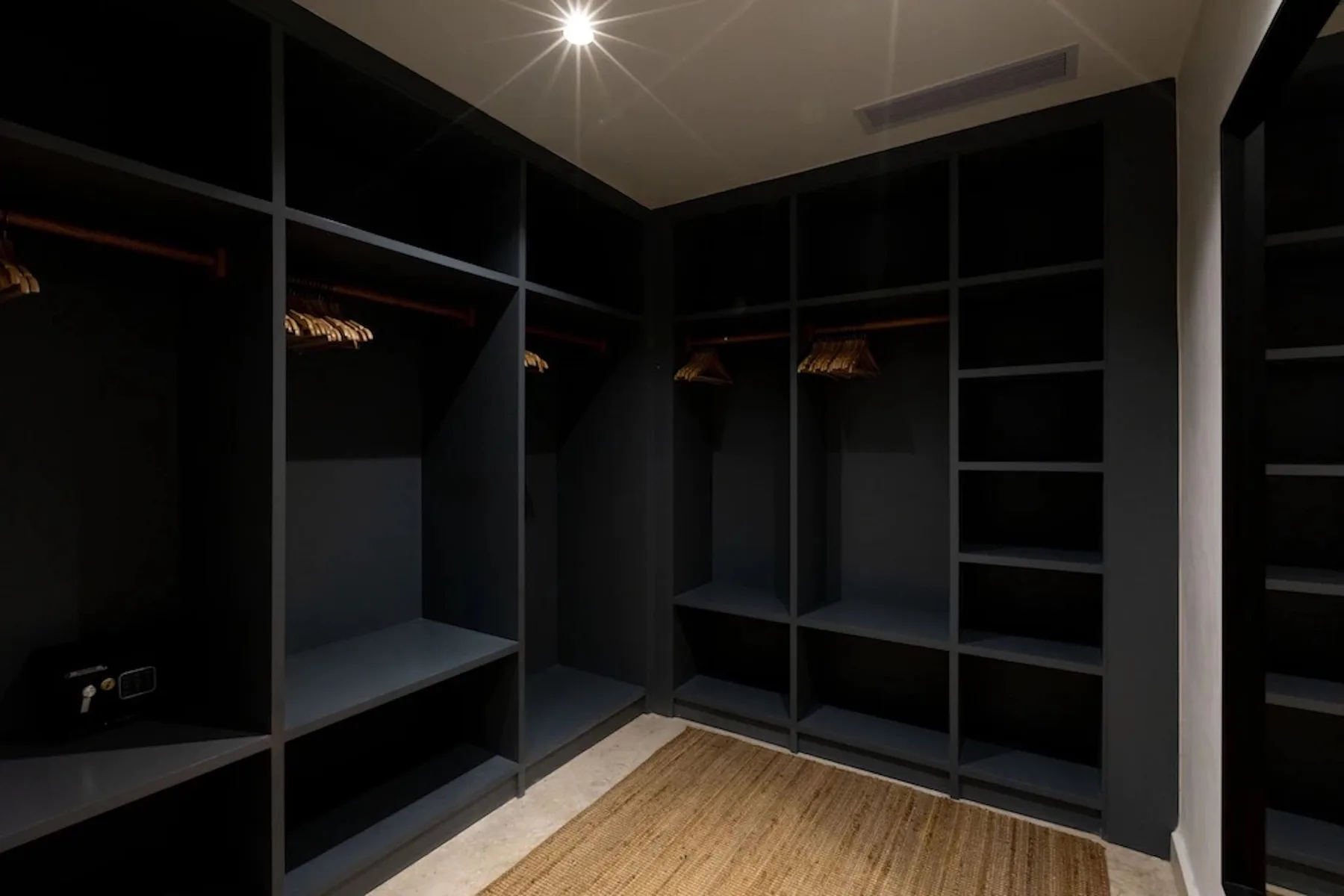 A walk-in closet with dark open shelving and hanging space.