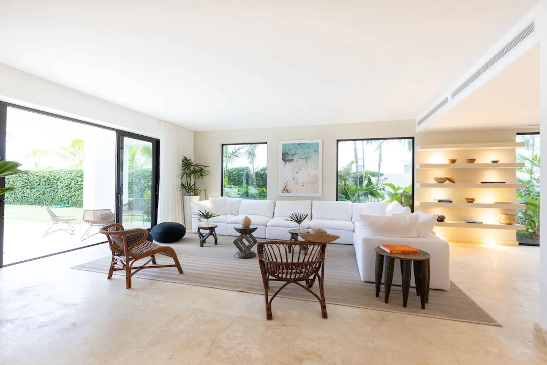 A bright living room with white seating arranged around a low coffee table.
