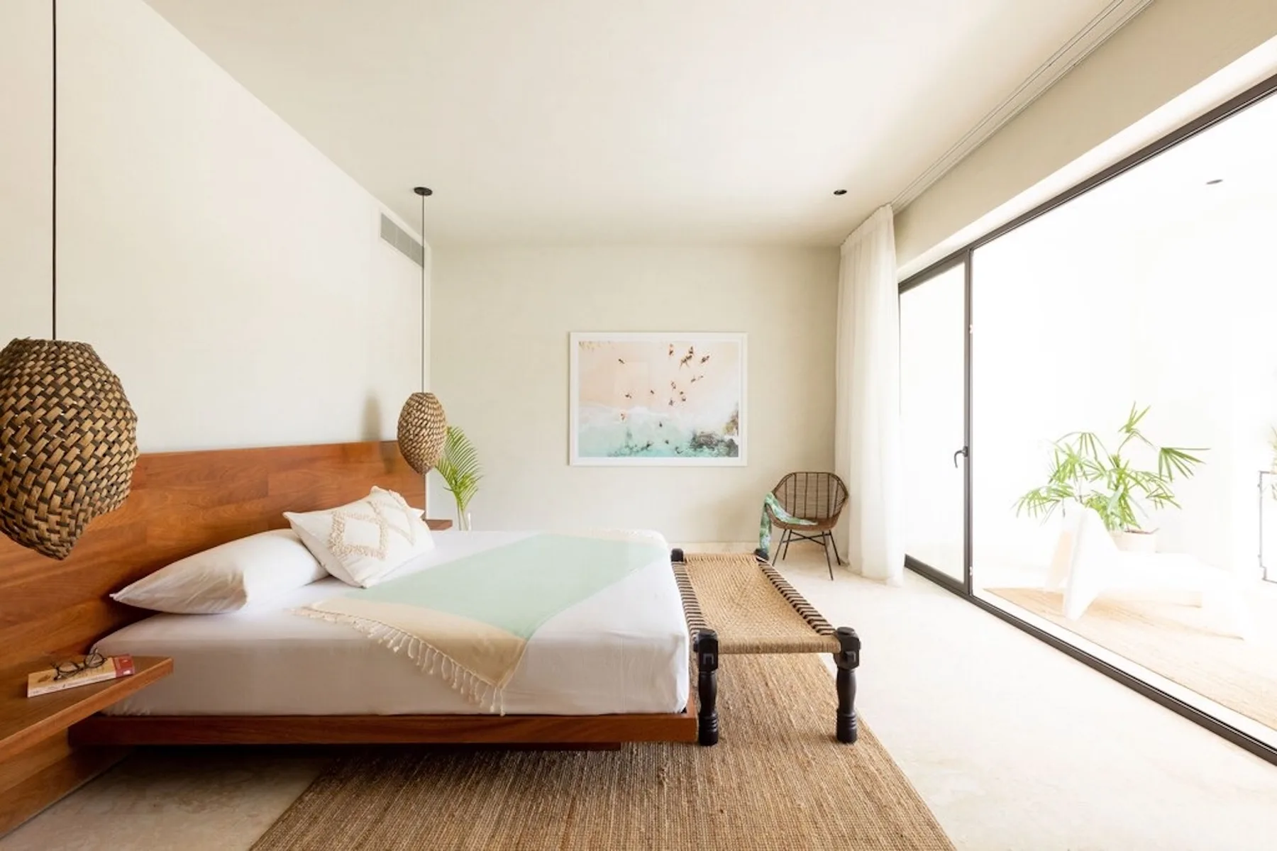 A bright bedroom with a bed beside a large glass sliding door.