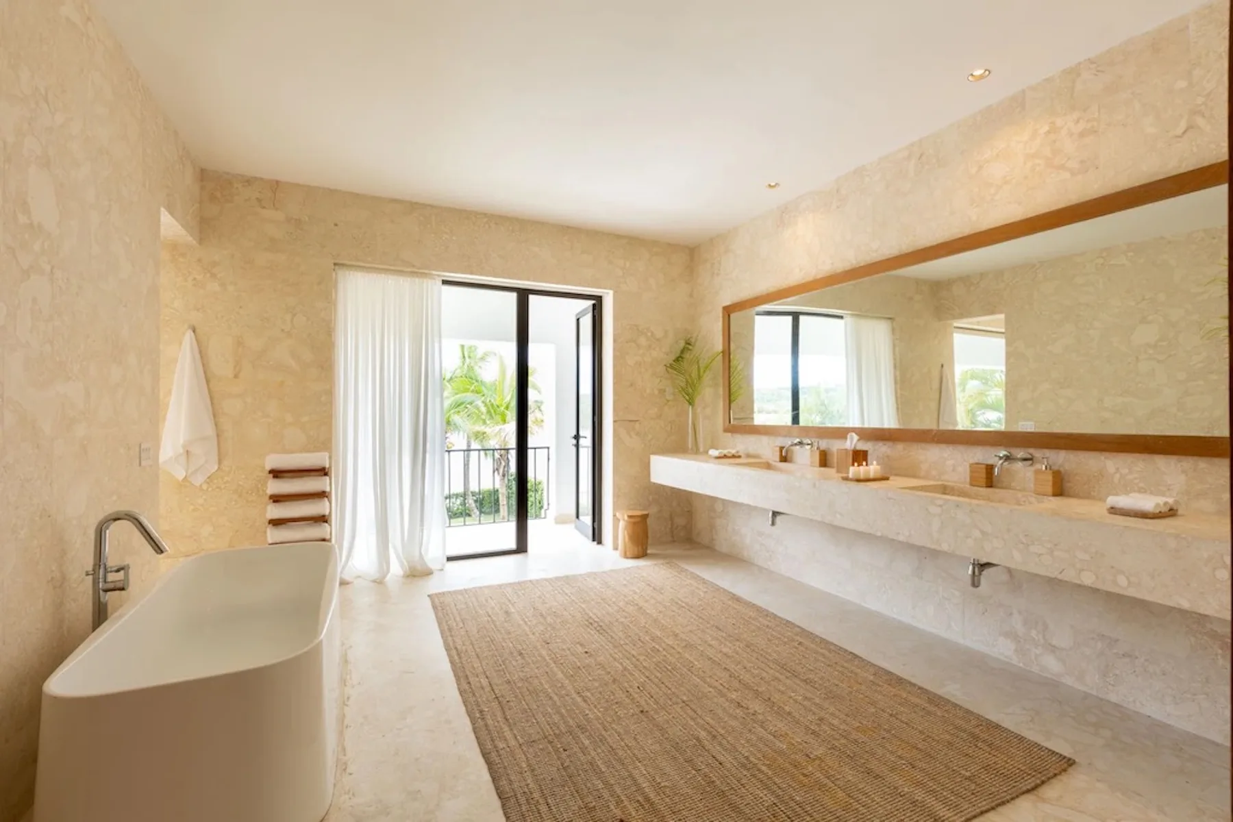 A bright bathroom with a freestanding bathtub, long vanity, and large mirror.
