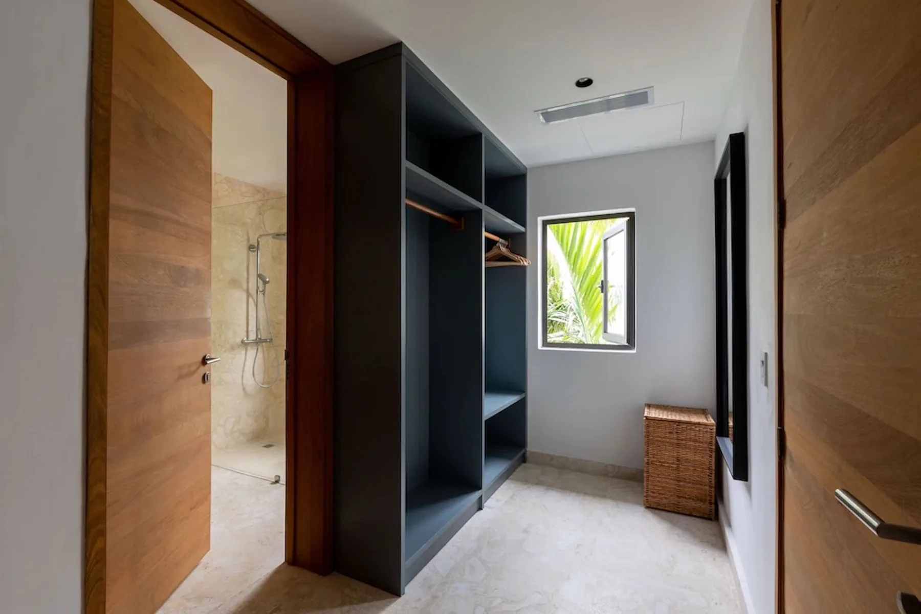 A dressing area with open shelving, a window, and a woven hamper.