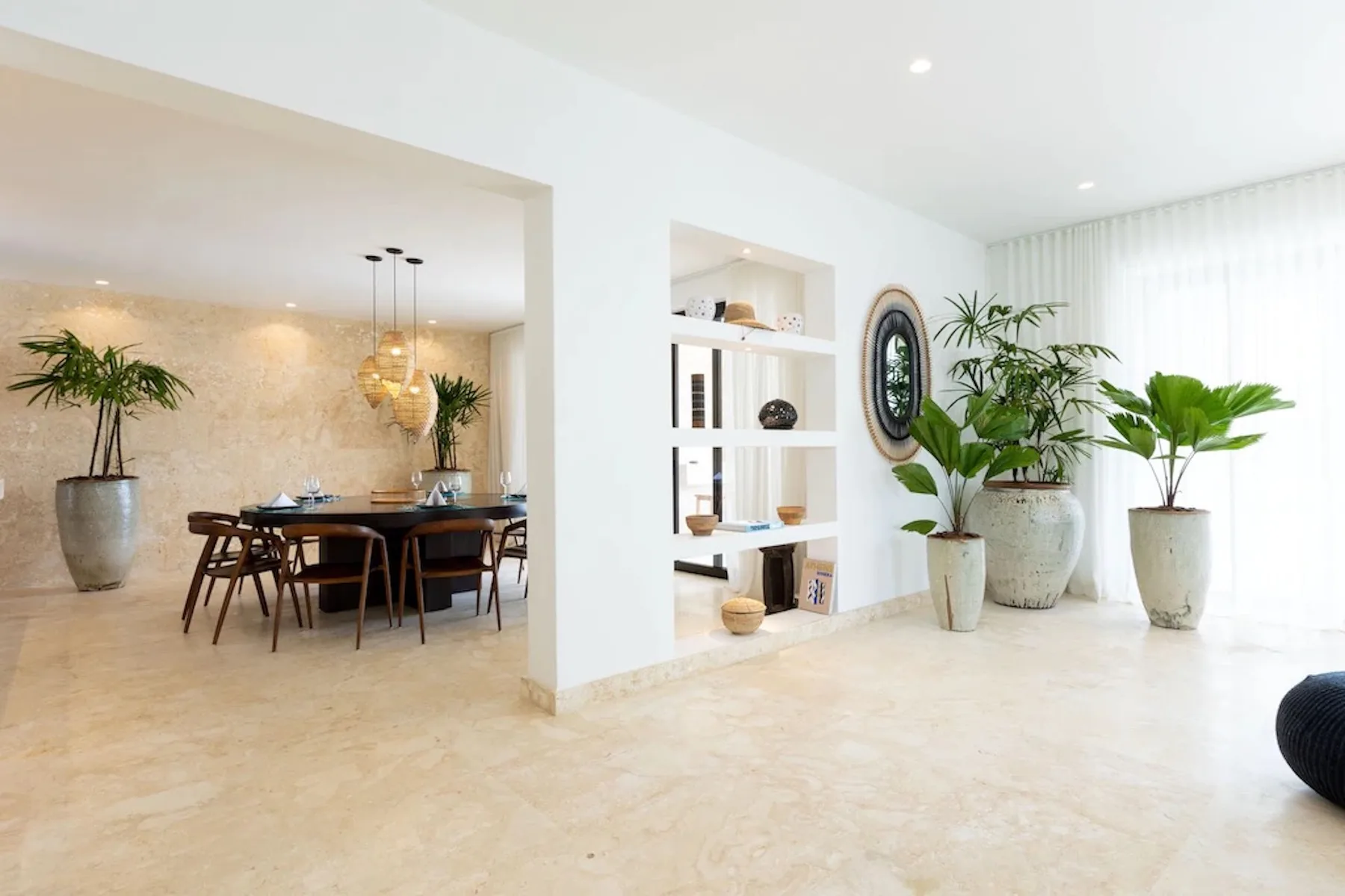 A bright living room opens onto a dining area, with plants beside the window.