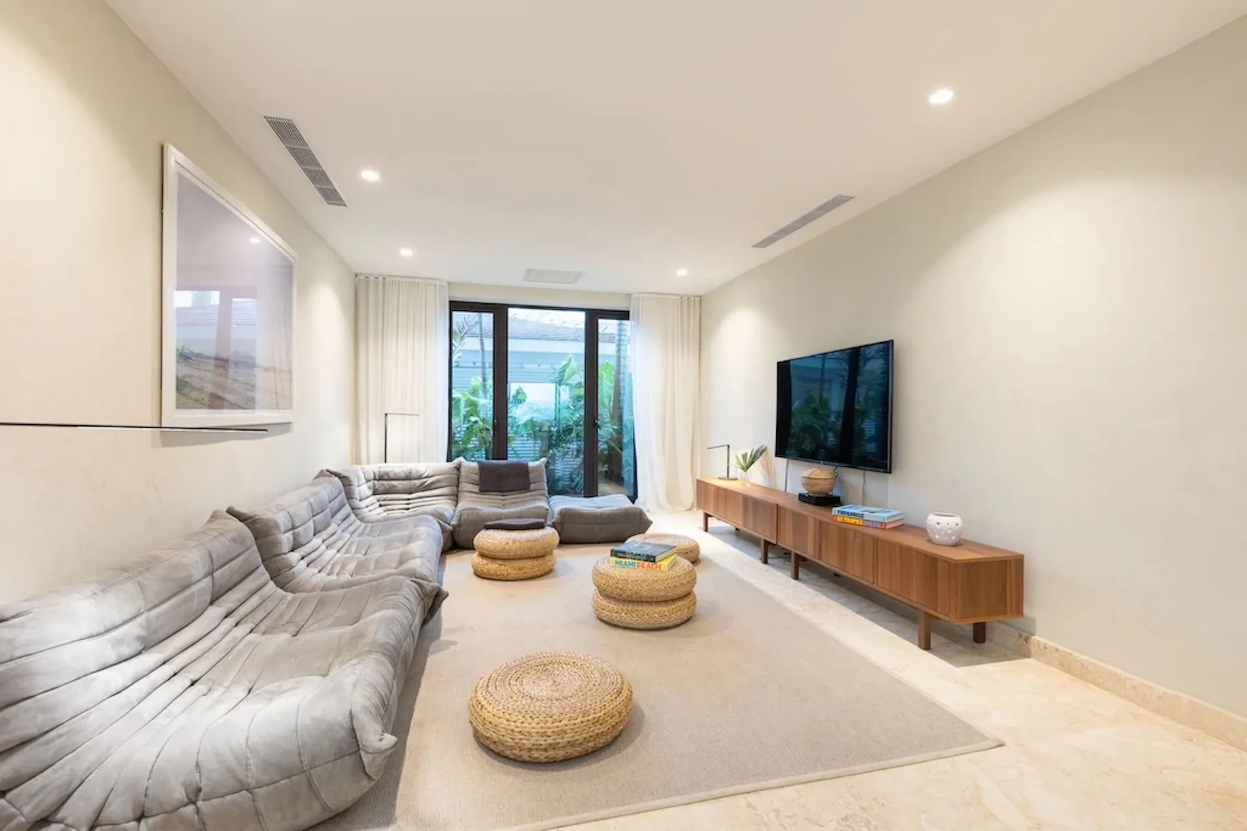 A bright living room with seating, a television, and a rug.