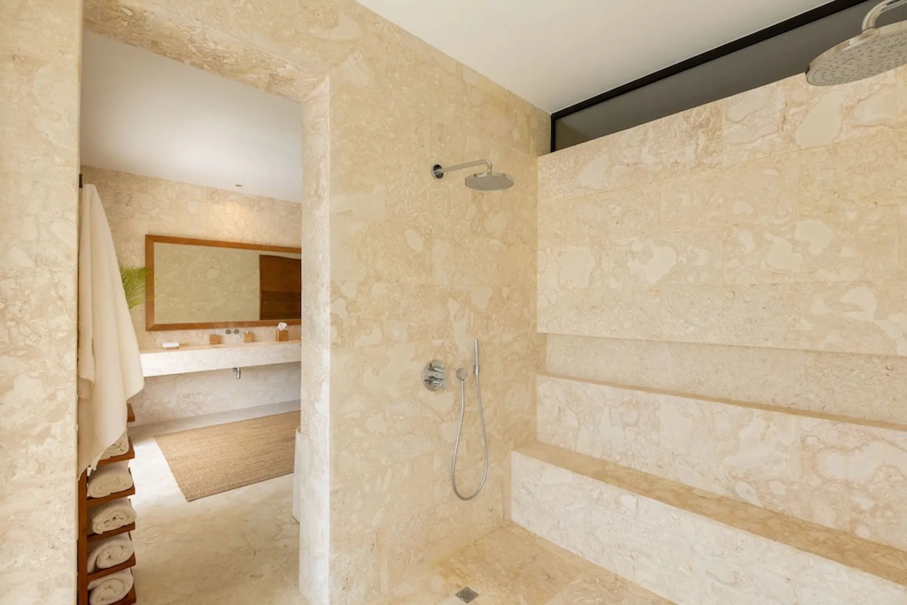 A tiled bathroom with a wall-mounted shower and an open vanity area.