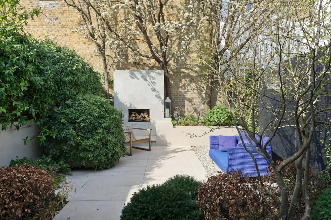 Un patio exterior con una chimenea empotrada y asientos azules.