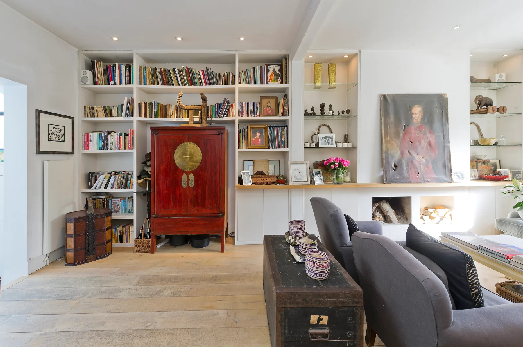 Una sala luminosa con estanterías empotradas y un mueble rojo.
