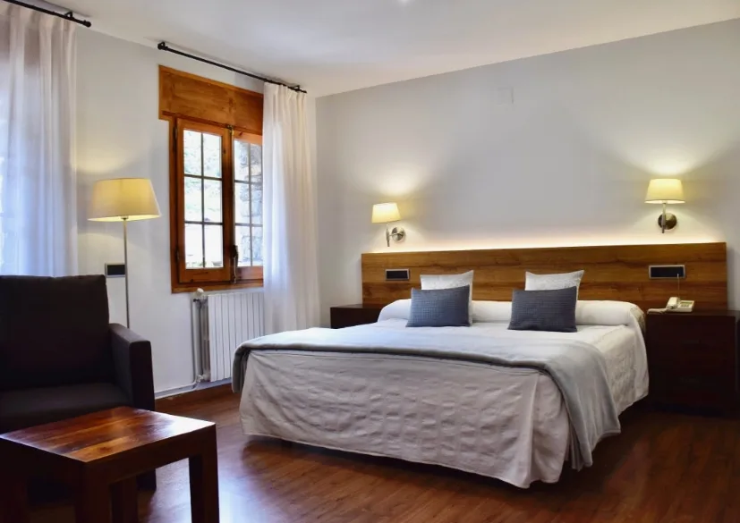 Habitación doble superior con cama de matrimonio, mesita de noche y sillones