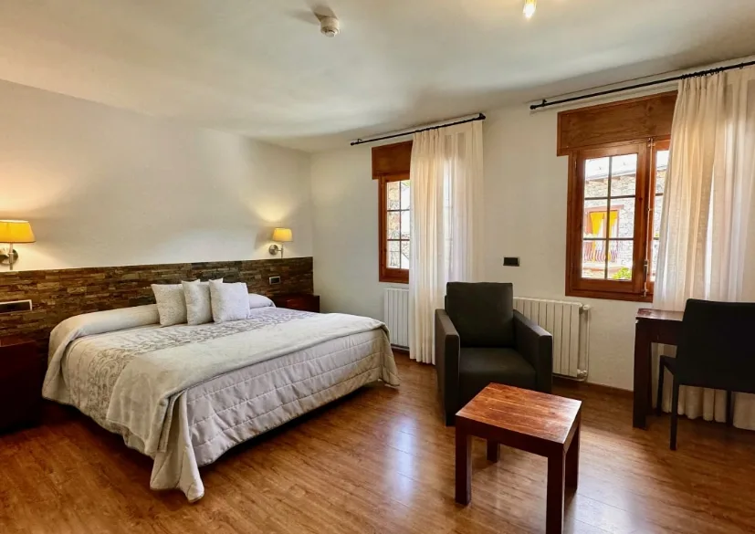 Habitación doble superior con cama de matrimonio, mesitas de noche y sillones
