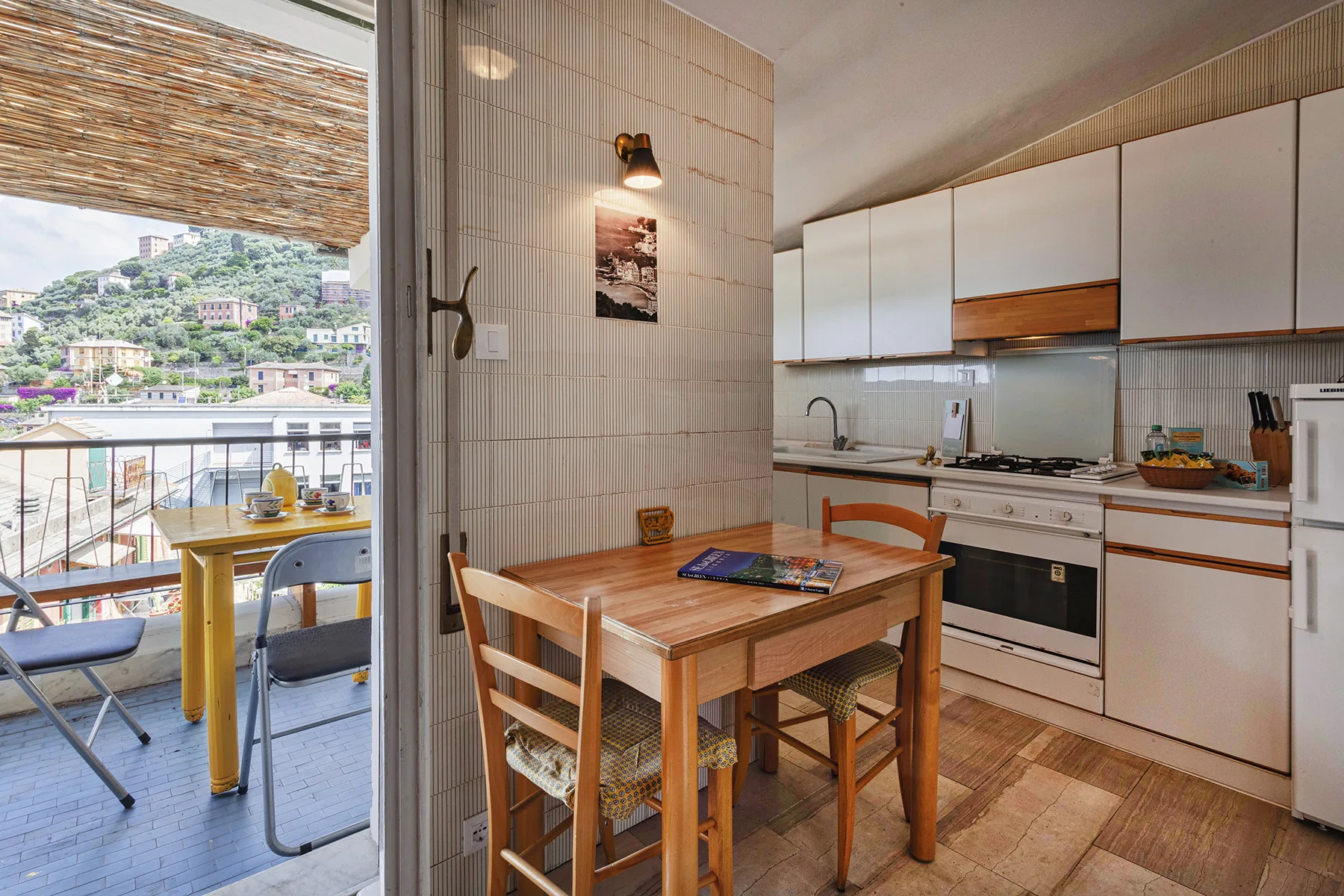 Comedor junto a una cocina compacta, con puertas de vidrio que dan a un balcón.