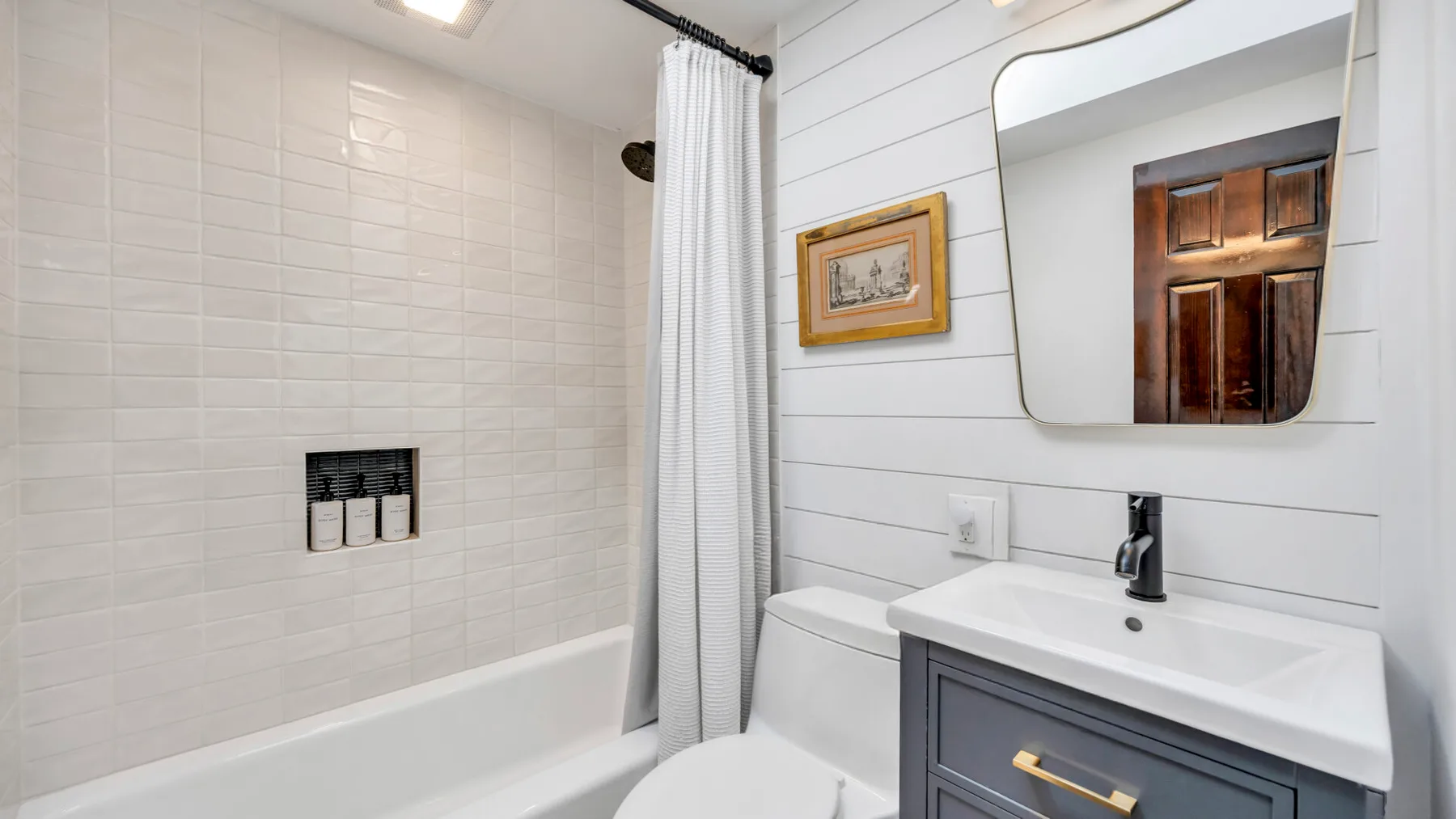 Un baño luminoso con bañera, cortina de ducha y lavabo con mueble.