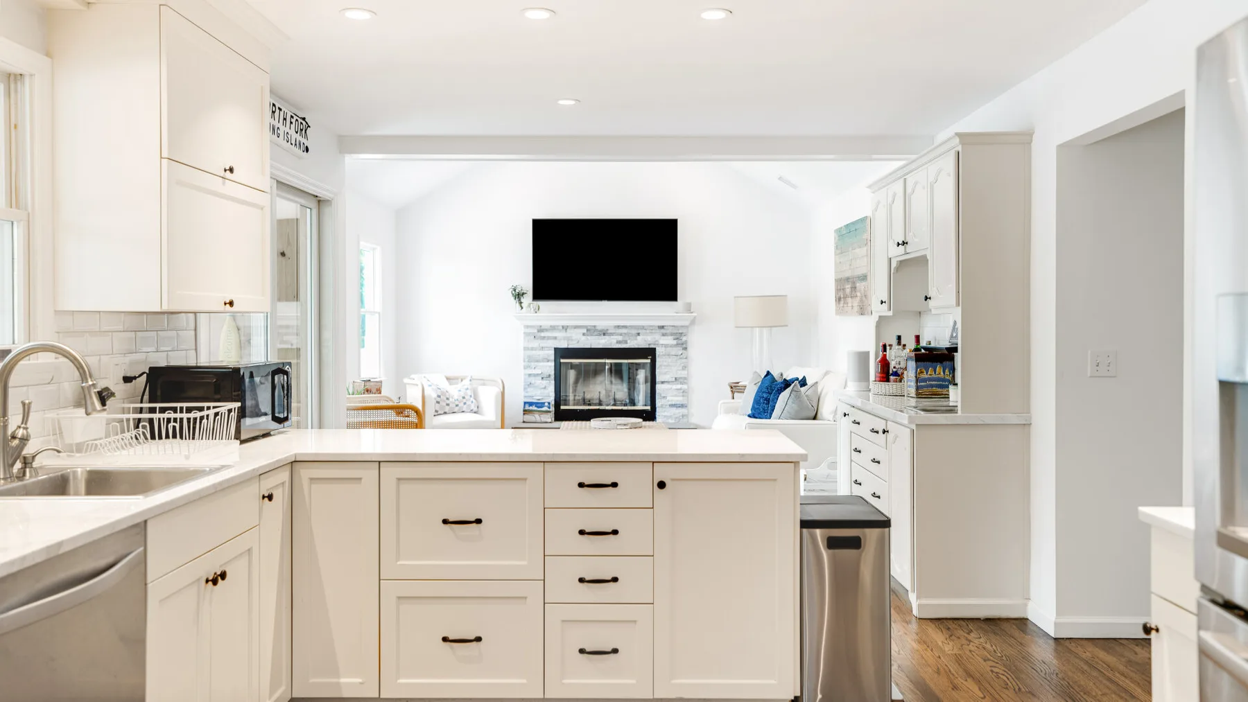 A bright kitchen with a central island and a living area beyond.