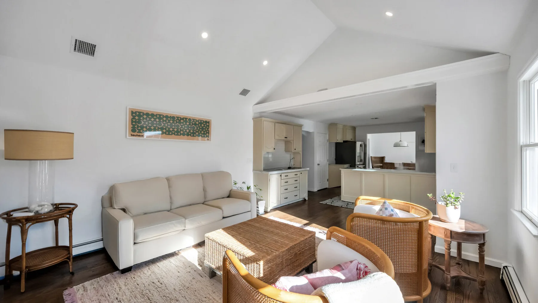 A bright living room with a sofa, wicker seating, and a low coffee table.