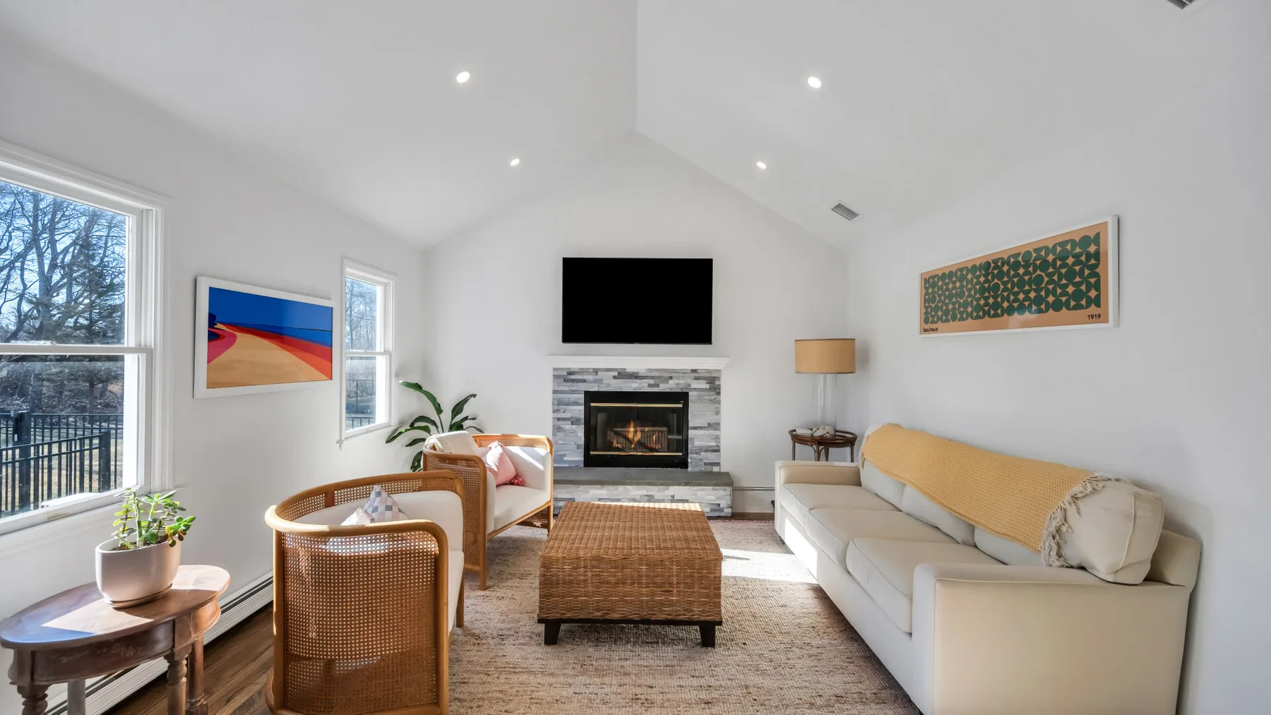 A bright living room with a television above the fireplace and seating around a coffee table.