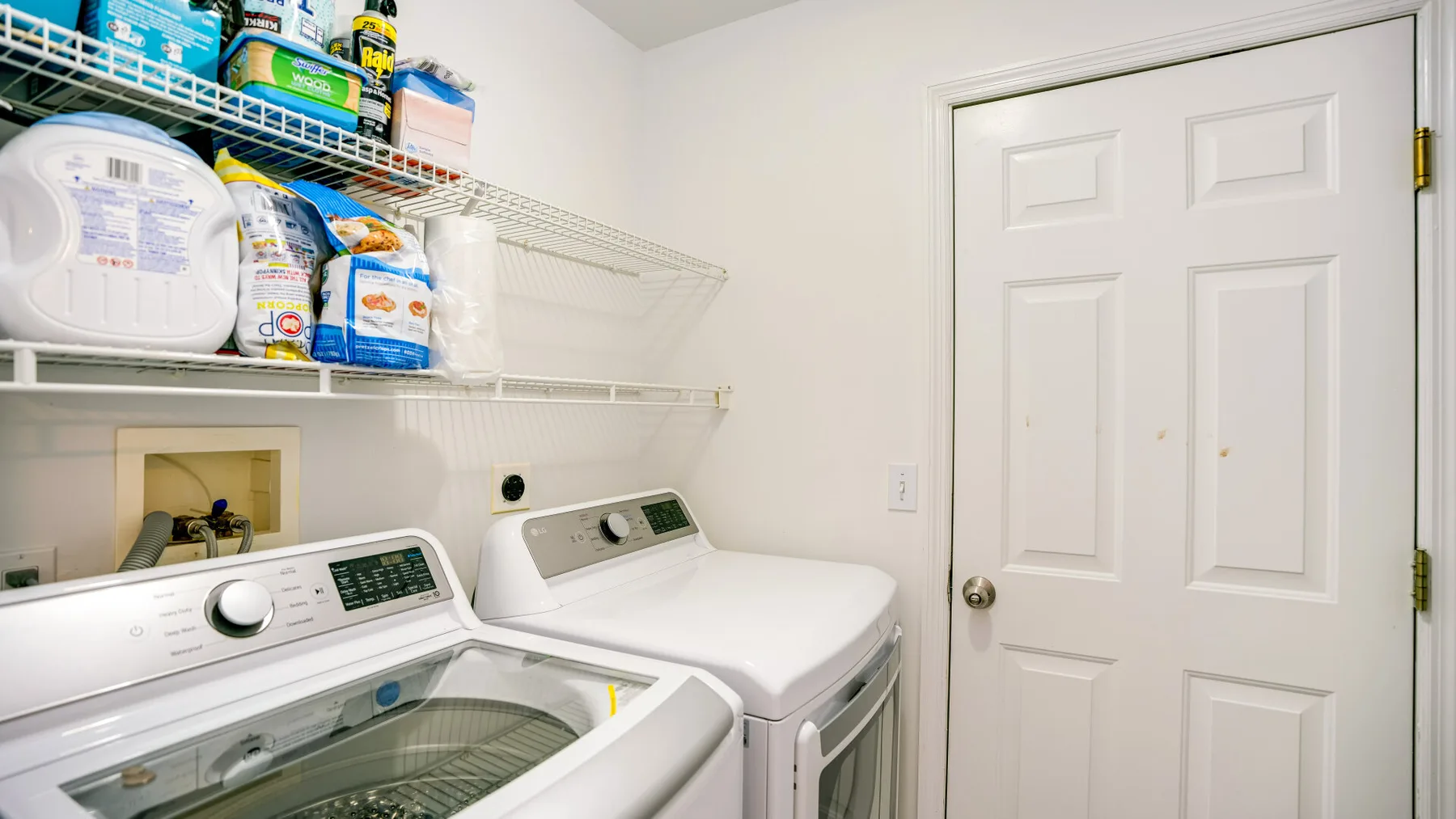 A laundry room with a washing machine, dryer, and shelves of supplies.