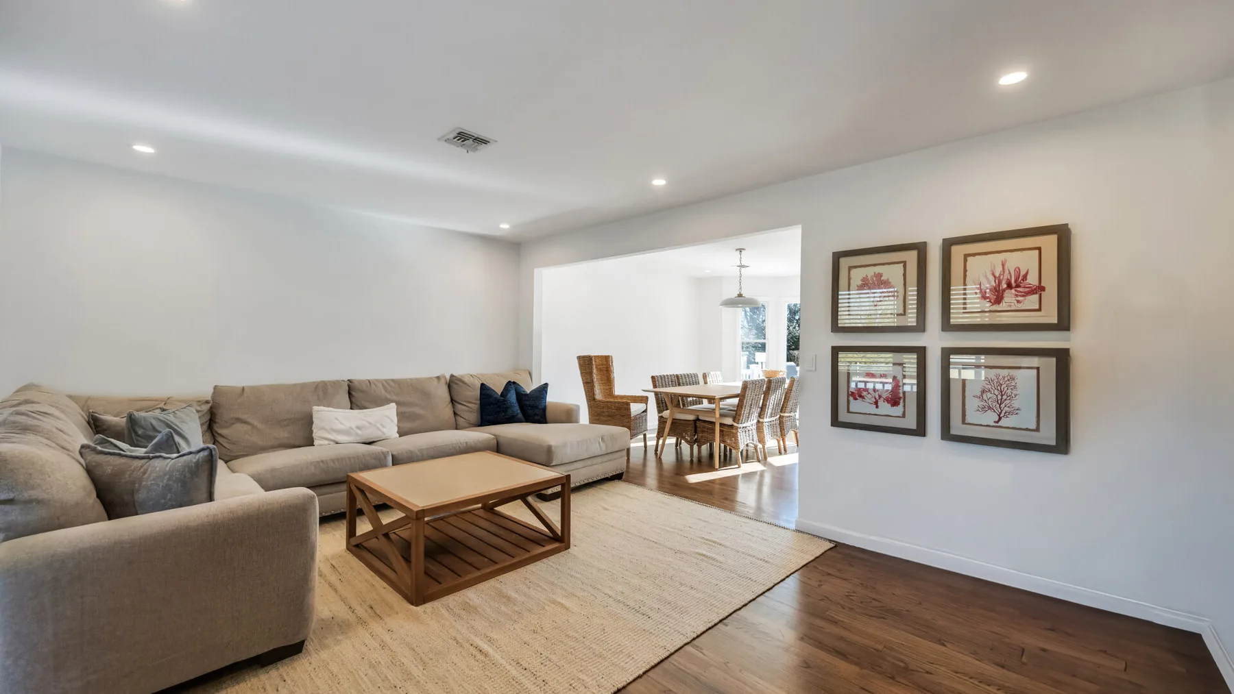 A bright living room with seating, a coffee table, and framed artwork.