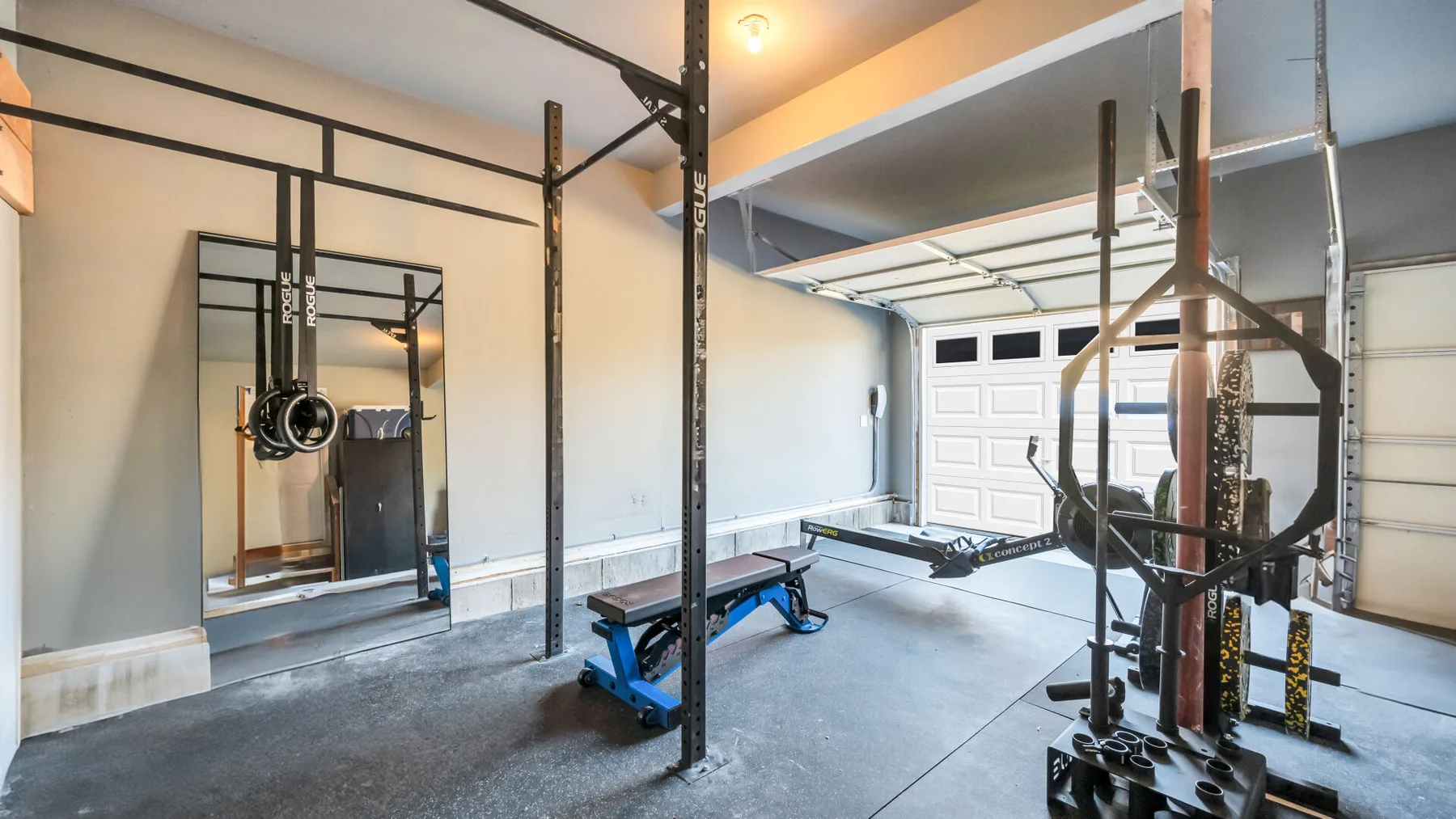 A home gym with exercise equipment and a bench on the floor.