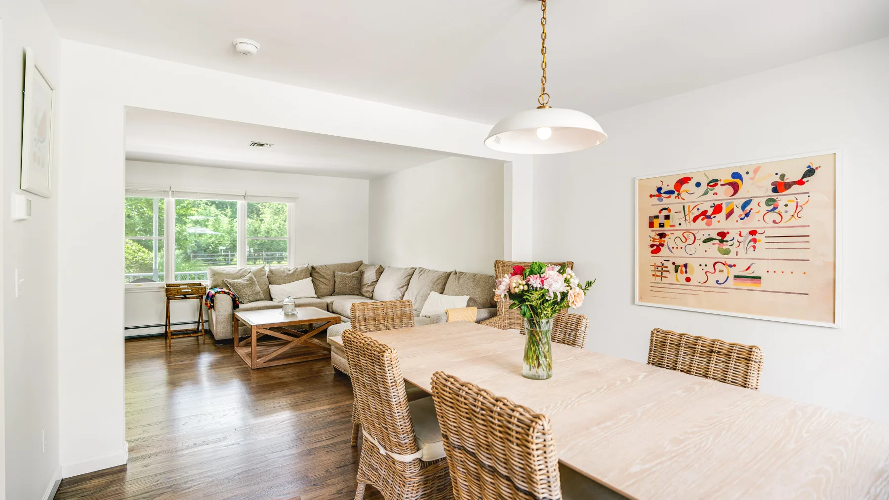 A dining area with woven seating and a living area visible beyond.